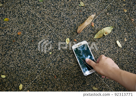 men hand pick a broken smart phone from floor  92313771