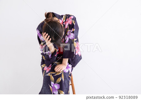 A woman wearing a yukata and holding her head Japan 92318089