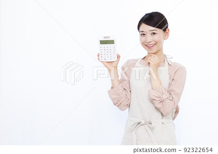 A housewife in her thirties thinking with a calculator and smiling A housewife in her thirties thinking with a calculator and smiling 92322654