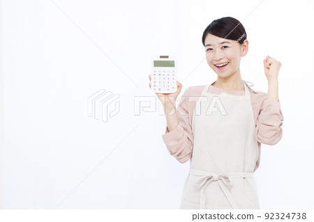 一個三十多歲的家庭主婦拿著計算器做膽量姿勢 92324738