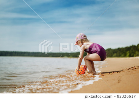 cute little girl playing with rubber ball in sea 92326617