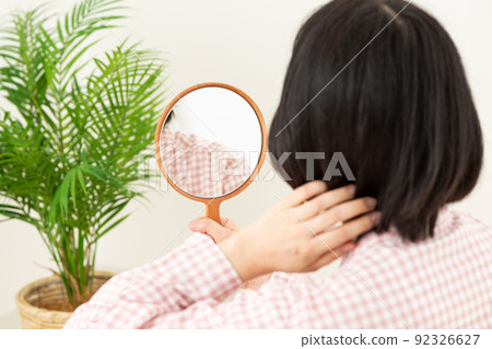 Middle woman looking in the hand mirror in the bedroom Middle woman looking in the hand mirror in the bedroom 92326627