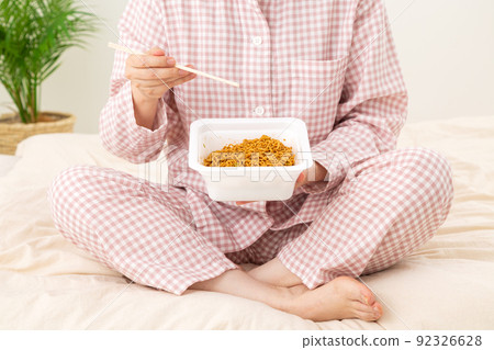 Middle-aged woman eating junk food midnight snack in the bedroom Middle-aged woman eating junk food midnight snack in the bedroom 92326628