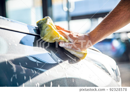 A man washes his car with foam at a self-service car wash, close-up. A man washes his car with foam at a self-service car wash, close-up. 92328578