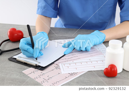 Female doctor write prescription into clipboard on table 92329132