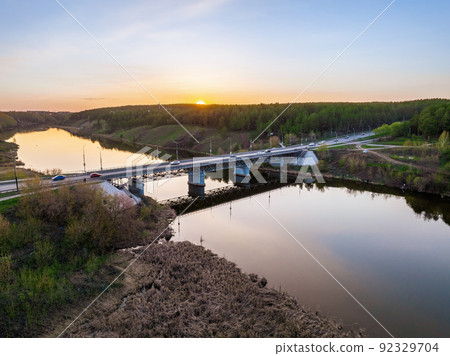 Beautiful view of the bridge across the Iset river in the city of Kamensk-Uralsky at sunset in spring. Kamensk-Uralskiy, Sverdlovsk region, Ural mountains, Russia. 92329704