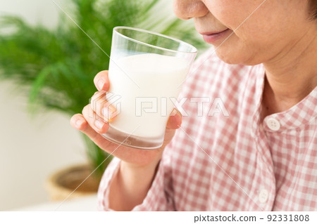 臥室裡穿著睡衣喝牛奶的中產婦女 臥室裡穿著睡衣喝牛奶的中產婦女 92331808