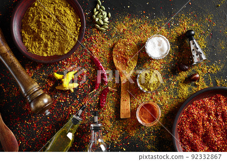 Assorted spices on dark black background. Seasonings for food. Curry, paprika, pepper, cardamom, turmeric. Top view. 92332867