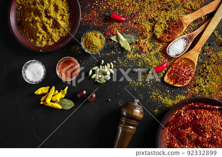 Set of indian spices on black background - green cardamom, turmeric powder, coriander seeds, cumin, and chili, top view Set of indian spices on black background - green cardamom, turmeric powder, coriander seeds, cumin, and chili, top view 92332899