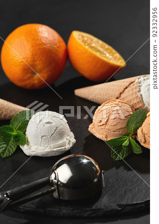Close-up shot of a creamy and orange ice cream served on a dark slate, black background. Close-up shot of a creamy and orange ice cream served on a dark slate, black background. 92332956