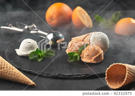 Close-up shot of a creamy and orange ice cream served on a dark slate, black background. Close-up shot of a creamy and orange ice cream served on a dark slate, black background. 92332975