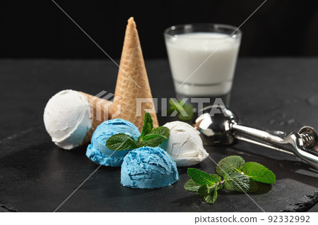 Close-up shot of a creamy and blueberry ice cream served on a dark slate, black background. 92332992