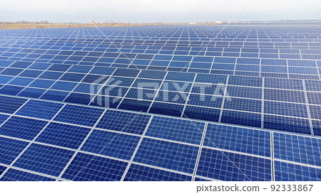Aerial drone view flight over solar panels on sunny day close-up. Photovoltaic solar panel. Moving over solar panels with sun glare. Production of renewable alternative energy. Green ecological energy Aerial drone view flight over solar panels on sunny day close-up. Photovoltaic solar panel. Moving over solar panels with sun glare. Production of renewable alternative energy. Green ecological energy 92333867