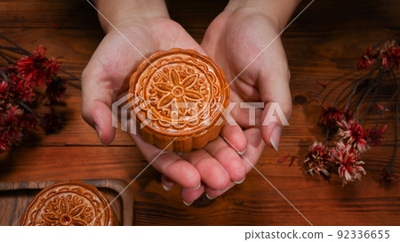 Hands holding round shaped Chinese traditional mooncake. Mid Autumn festival and Chinese traditional festival concept 92336655