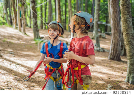 Friends on the ropes course. Young people in safety equipment are obstacles on the road rope Portrait of a disgruntled girl sitting at a cafe table 92338554