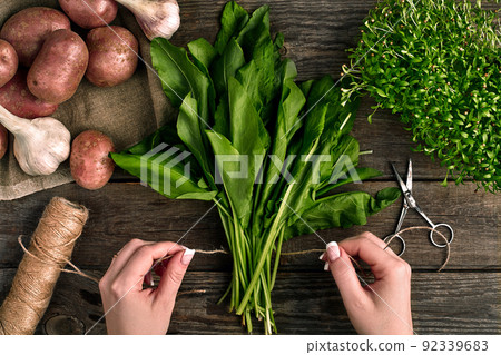 Woman hands holding fresh organic spinach leaves. Vegetables, onion, garlic, potatoes, spinach, lettuce leaves on wooden background Woman hands holding fresh organic spinach leaves. Vegetables, onion, garlic, potatoes, spinach, lettuce leaves on wooden background 92339683