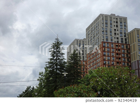 New modern block of flats in green area with blue sky. Cityscape - apartments exteriors, residentional area. High quality photo 92340419