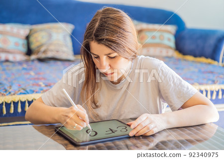 Calligrapher Young Woman writes phrase on digital tablet. Inscribing ornamental decorated letters. Calligraphy, graphic design, lettering, handwriting, creation 92340975