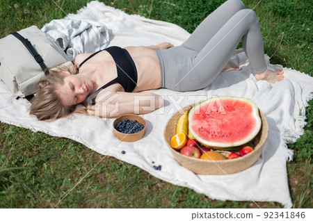 Girl relaxing and eat watermelon outdoor near lake. Picnic in nature Girl relaxing and eat watermelon outdoor near lake. Picnic in nature 92341846