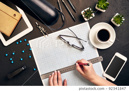Office desk background hand with pen writing construction project ideas concept. With tablet, drawing equipment and a cup of coffee. View from above Office desk background hand with pen writing construction project ideas concept. With tablet, drawing equipment and a cup of coffee. View from above 92341847