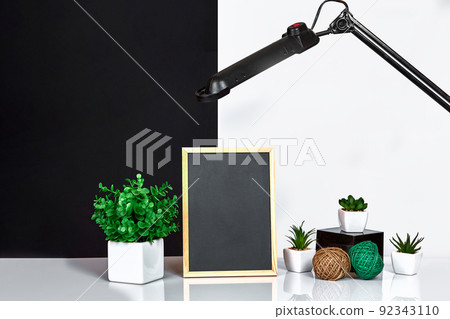 Wooden frame with black place for text. Mock up. Stylish room interior. Green plant in a white pot on black-white wall background 92343110