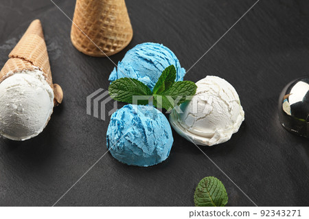 Close-up shot of a creamy and blueberry ice cream served on a dark slate, black background. 92343271