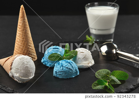 Close-up shot of a creamy and blueberry ice cream served on a dark slate, black background. 92343278