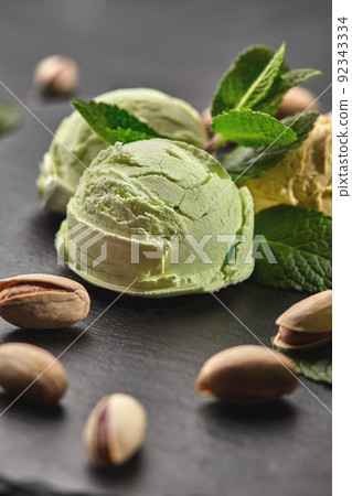 Gourmet pistachio ice cream served on a stone slate over a black background. 92343334