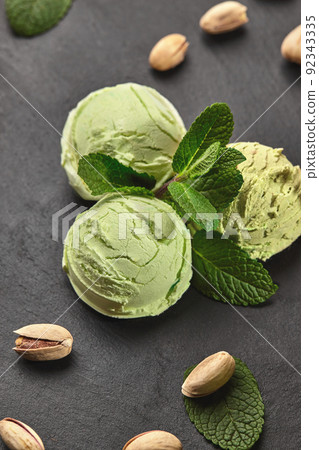 Gourmet pistachio ice cream served on a stone slate over a black background. Gourmet pistachio ice cream served on a stone slate over a black background. 92343335