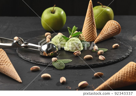 Gourmet pistachio ice cream served on a stone slate over a black background. Gourmet pistachio ice cream served on a stone slate over a black background. 92343337