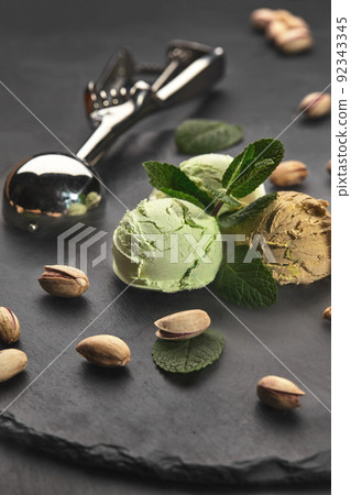 Gourmet chocolate and pistachio ice cream served on a stone slate over a black background. 92343345