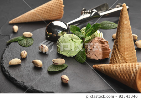 Gourmet chocolate and pistachio ice cream served on a stone slate over a black background. Gourmet chocolate and pistachio ice cream served on a stone slate over a black background. 92343346