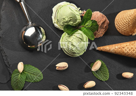 Gourmet chocolate and pistachio ice cream served on a stone slate over a black background. 92343348