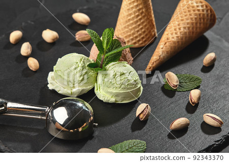 Gourmet chocolate and pistachio ice cream served on a stone slate over a black background. Gourmet chocolate and pistachio ice cream served on a stone slate over a black background. 92343370