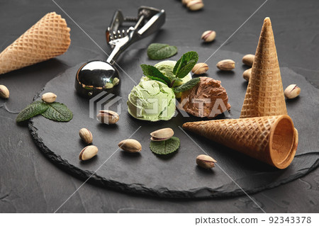 Gourmet chocolate and pistachio ice cream served on a stone slate over a black background. Gourmet chocolate and pistachio ice cream served on a stone slate over a black background. 92343378