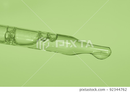 Pipette with liquid essence on a light green background. This is the consistency of micellar water. The concept of an extract for cosmetic and therapeutic purposes. High quality photo Pipette with liquid essence on a light green background. This is the consistency of micellar water. The concept of an extract for cosmetic and therapeutic purposes. High quality photo 92344762