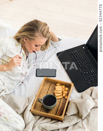 Young woman checking news in her smartphone in bed. Freelancer morning. 92344778