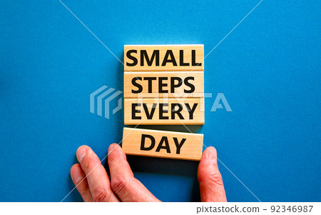 Small steps every day symbol. Concept words Small steps every day on wooden blocks. Businessman hand. Beautiful blue table blue background. Small steps every day business concept. Copy space. 92346987