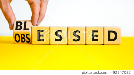 Blessed or obsessed symbol. Businessman turns wooden cubes and changes the concept word Obsessed to Blessed. Beautiful yellow table white background. Business blessed or obsessed concept. Copy space. 92347022