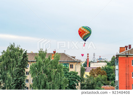 Colorful balloons fly in the sky above the roofs of high-rise buildings in a provincial city Colorful balloons fly in the sky above the roofs of high-rise buildings in a provincial city 92348408