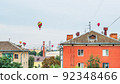 Many colorful balloons fly in the sky above the roofs of high-rise buildings in a provincial city 92348466