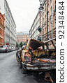 A burnt-out, rusted-out car on the street of a European city, vertical photo 92348484