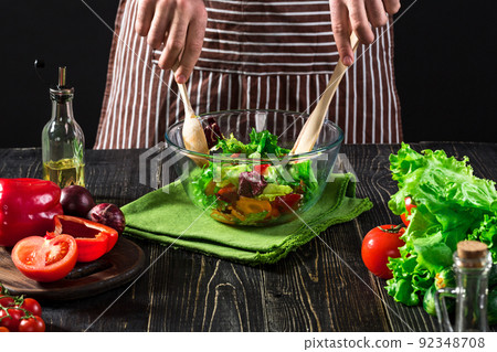 Man preparing salad with fresh vegetables on a wooden table. Cooking tasty and healthy food Man preparing salad with fresh vegetables on a wooden table. Cooking tasty and healthy food 92348708