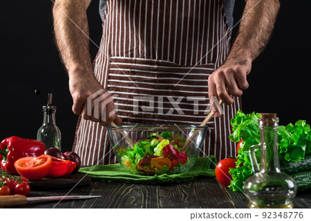 Man preparing salad with fresh vegetables on a wooden table. Cooking tasty and healthy food Man preparing salad with fresh vegetables on a wooden table. Cooking tasty and healthy food 92348776