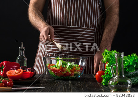Man preparing salad with fresh vegetables on a wooden table. Cooking tasty and healthy food 92348858