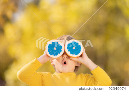 Surprised child holding slices of orange fruit like sunglasses Surprised child holding slices of orange fruit like sunglasses 92349074
