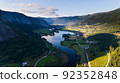 Scandinavian landscape with a village in the valley shadow, mountains, and river. View from above 92352848