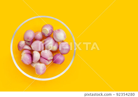 Fresh shallot in glass bowl on yellow background 92354280