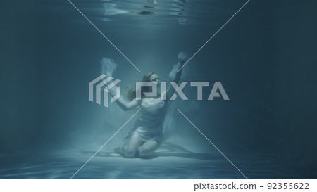 red-haired woman meditating underwater in white dress red-haired woman meditating underwater in white dress 92355622