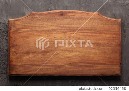 Wooden nameplate or sign board screwed at wall background. Front view of name plate 92356468